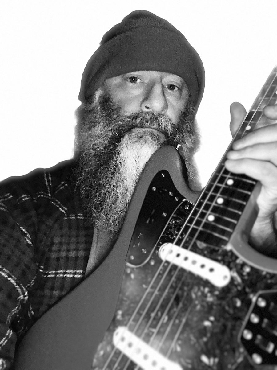 Black-and-white photograph of Greg Wiggs with an electric guitar