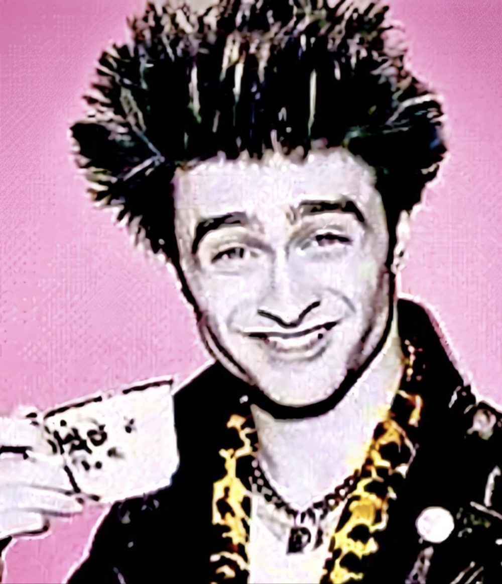 Greg Wiggs in pop-art style — spiked hair, leopard-print collar, holding a teacup against a pink background